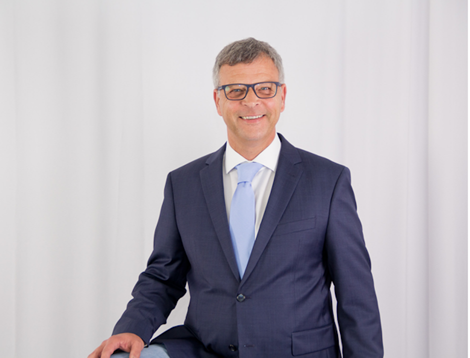 Mann mit Anzug und Brille lächelt in die Kamera