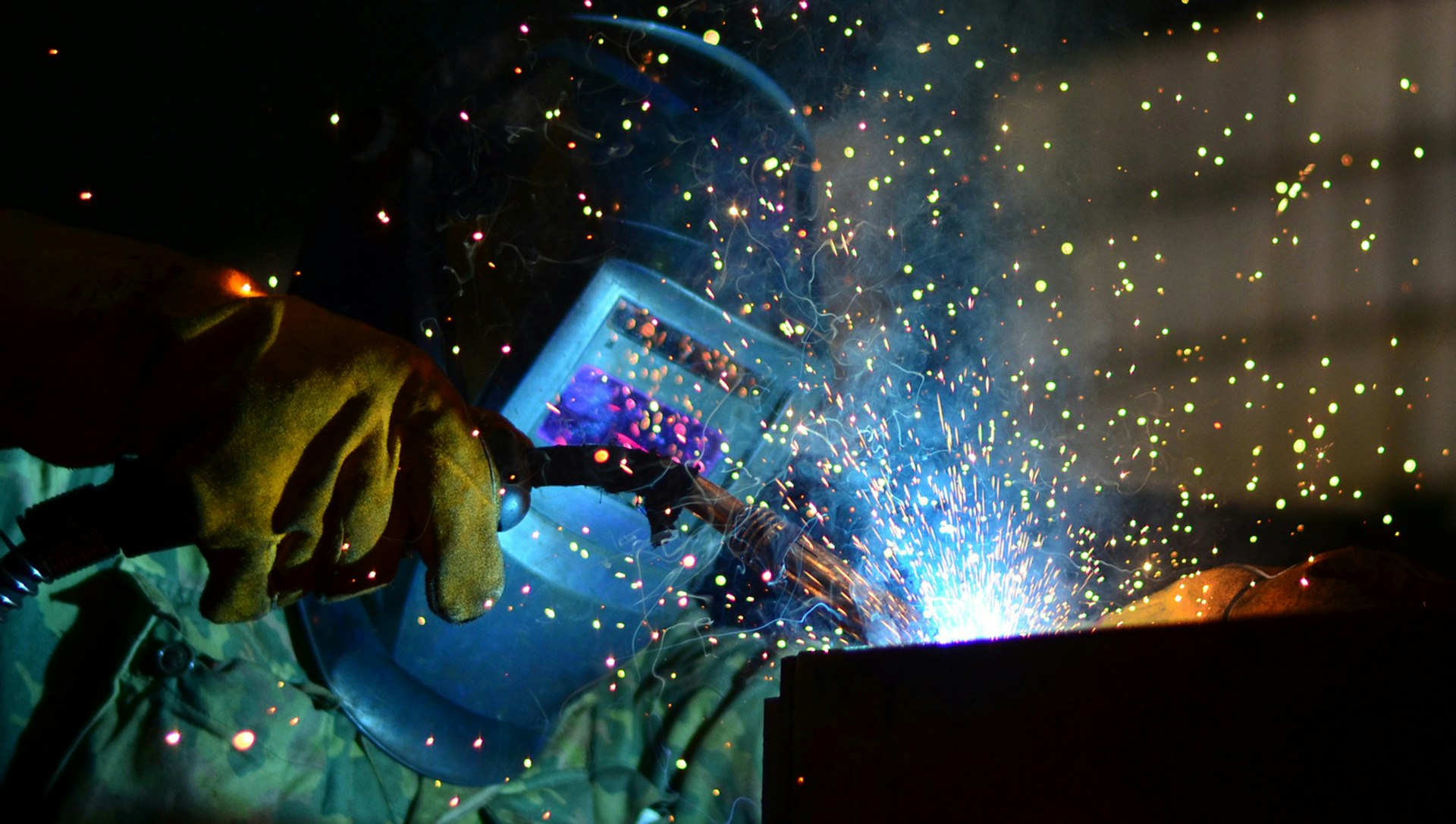 Person with helmet is welding, sparks and fume occur