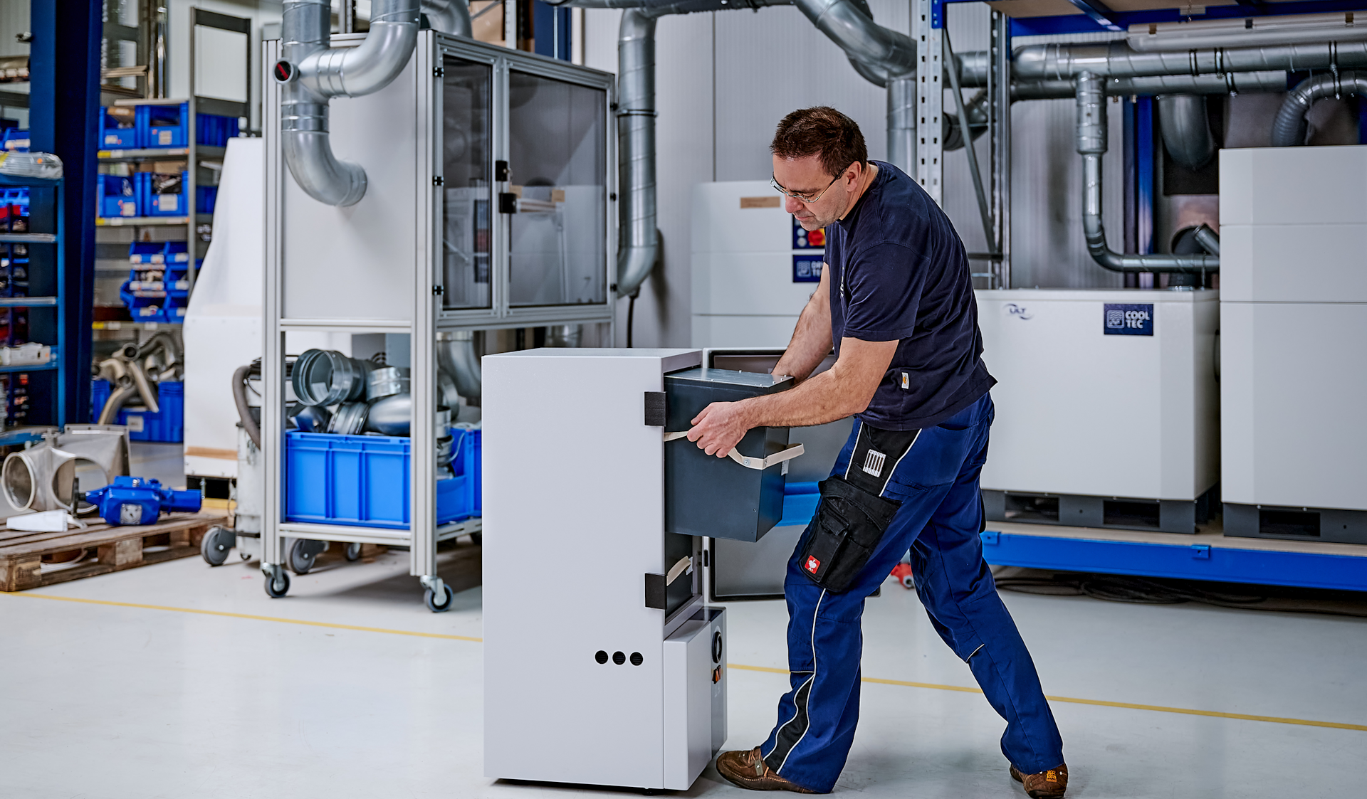 Man in work trousers changes a filter in an extraction system