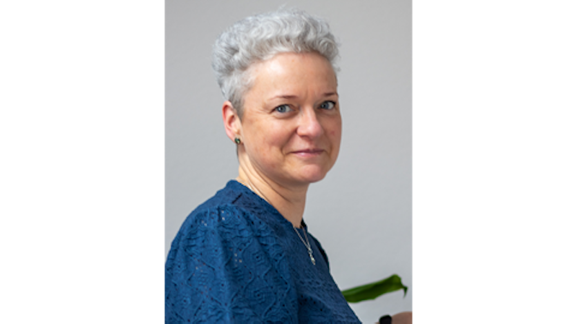 FRau mit kurzen grauen Haaren lächelt nach rechts
