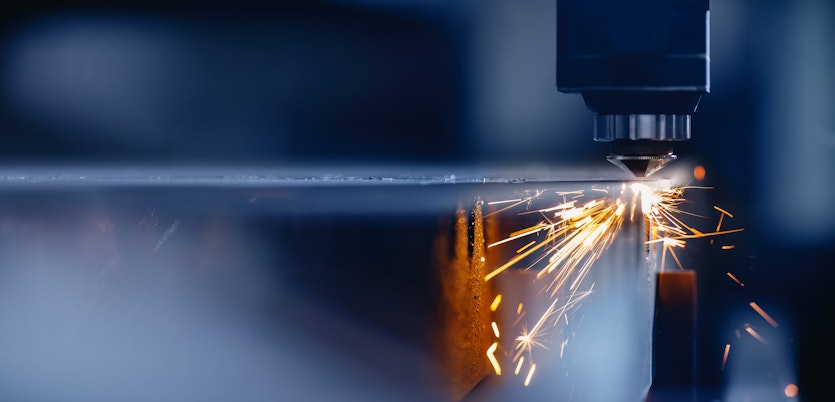 Maschine arbeitet an einer Metallplatte. Funken entstehen.