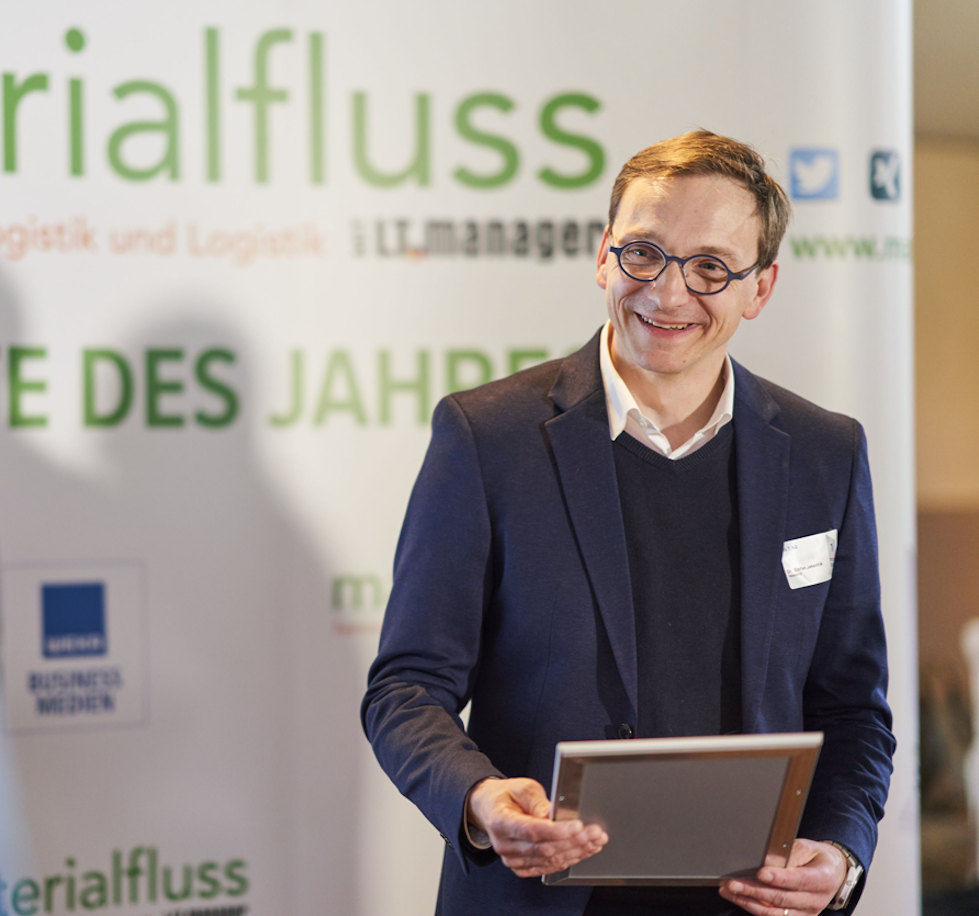 Mann mit Brille im Anzug freut sich über den Erhalt der Auszeichnung