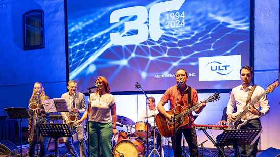 Sechs Musiker stehen auf einer Bühne und spielen Instrumente ...