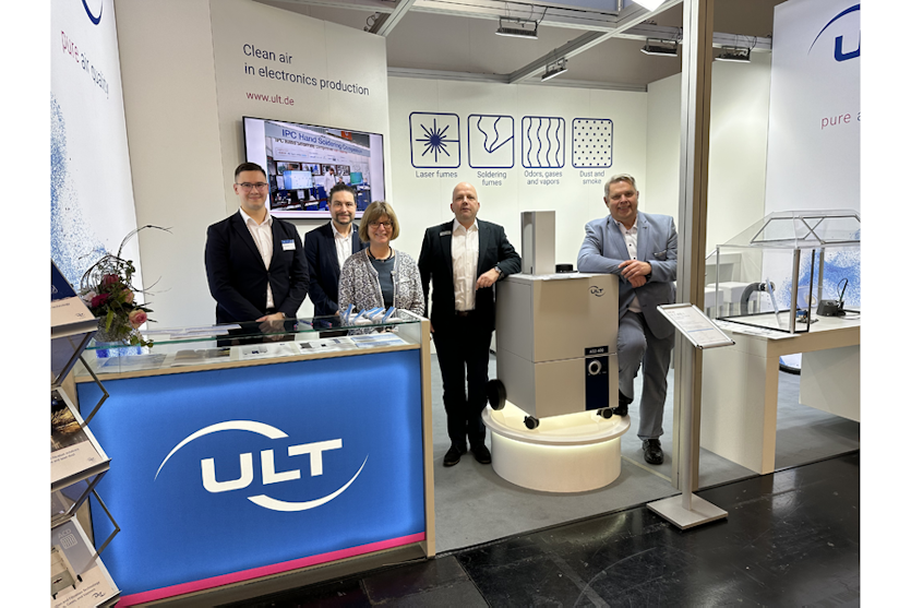 Five persons on the booth smiling into the camera