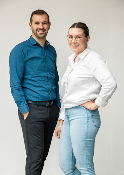 Zwei junge Menschen stehen benebeinander und lächeln