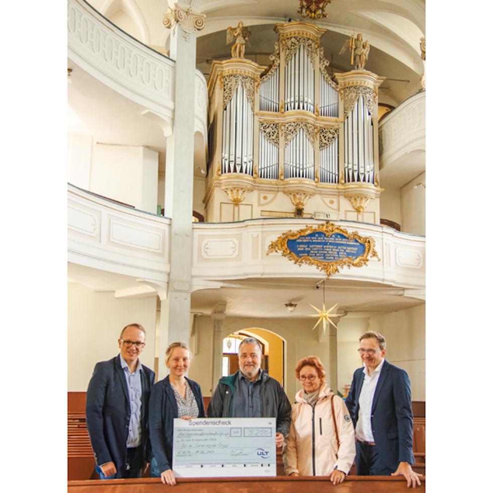 Lächelnde Menschen stehen vor der thronenden Orgel